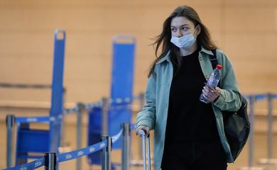 Mulher usando máscara de proteção caminha na área de embarque do aeroporto de Vnukovo, em Moscou