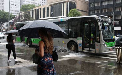 Ônibus joga água na calçada durante chuva na Avenida Paulista.
