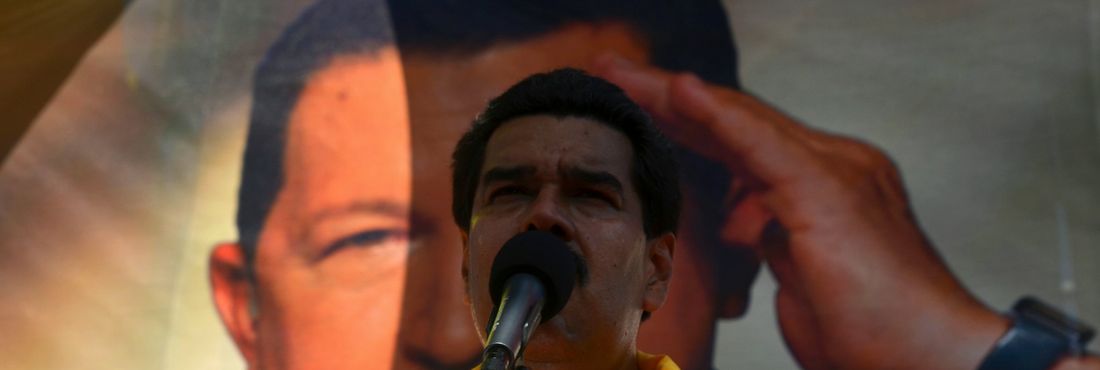 Nicolás Maduro com banner de Hugo Chávez ao fundo
