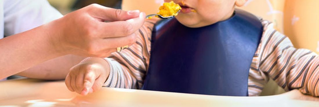 Bebê comendo papinha Vitamina pode ser encontrada em legumes amarelos, fígado bovino, leite, verduras e frutas