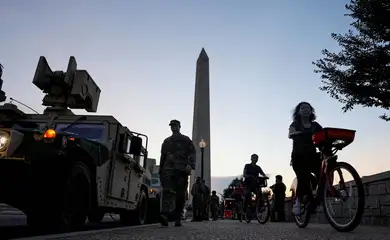 Tourists ride bicycles past U.S. Army National Guard Humvees near the Washington Monument after U.S. President Donald Trump announced a federal takeover of the Metropolitan Police Department under the Home Rule Act to assist with crime prevention in the nation's capital, Washington, D.C., U.S., August 12, 2025. REUTERS/Jonathan Ernst