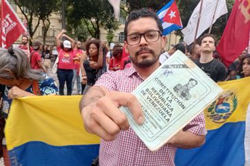 Rio de Janeiro (RJ), 05/01/2026 - Manifestante Ali Alvarez, de 31 anos, há oito anos no Brasil, mostra constituição da Venezuela durante ato na Cinelândia contra a invasão dos Estados Unidos na Venezuela. Foto: Gilberto Costa/Agência Brasil
