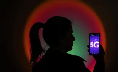 Brasília (DF) 21/01/2025 - Uma mulher segura um celular com a imagem da nova tecnologia 5G.
Desde 1 de janeiro de 2023, cidades com população igual ou superior a 500 mil habitantes começaram a receber o sinal do 5G. 
A Anatel espera que todas as cidades do país tenham esse tipo de rede até dezembro de 2029. 
Foto: Joédson Alves/Agência Brasil