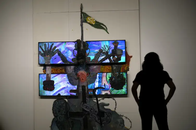 Joedson Alves/Agencia Brasil Brasilia 07/02/2023 - Uma mulher é vista em silhueta observando a obra sobre drywall e quatro monitores de TV da série Teatro Nagô Cartesiano. A cruz que penetra Pindorama, do artista, Thiago Martins de Melo, na Exposição Brasil futuro