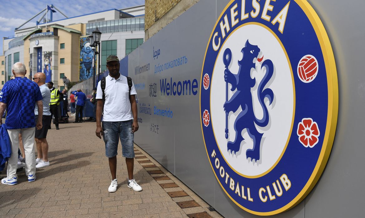 Torcedores ao lado do distintivo do Chelsea do lado de fora do estádio do clube, em Londres