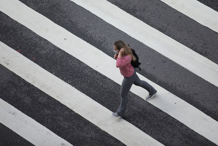 Mulher com máscara de proteção em avenida de São Paulo