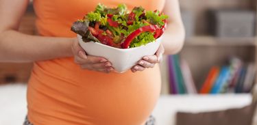 Close de mulher grávida com um prato de salada