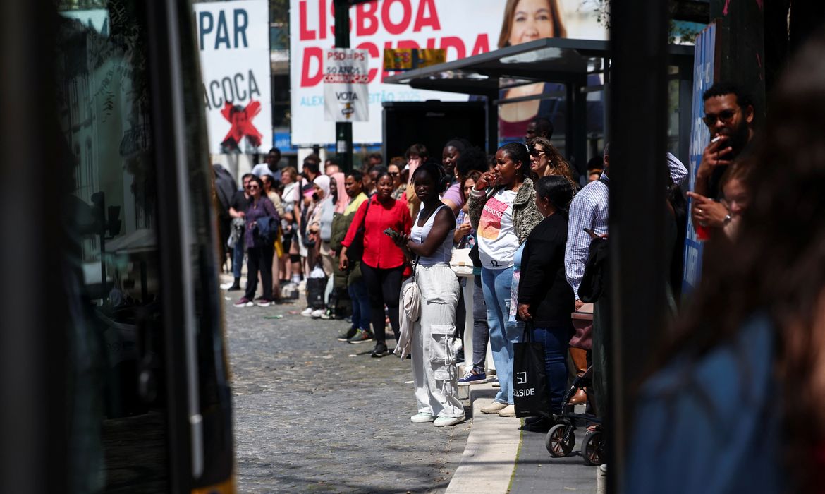 People stand at a bus stop after the metro was closed during a power outage, in Lisbon, Portugal, April 28, 2025. REUTERS/Pedro Nunes