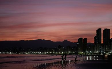 People walk on a beach during sunset in Praia Grande