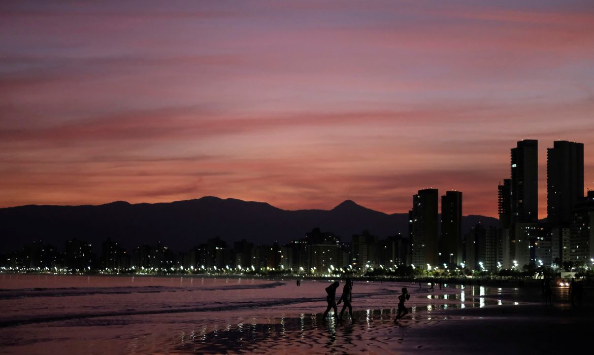 People walk on a beach during sunset in Praia Grande