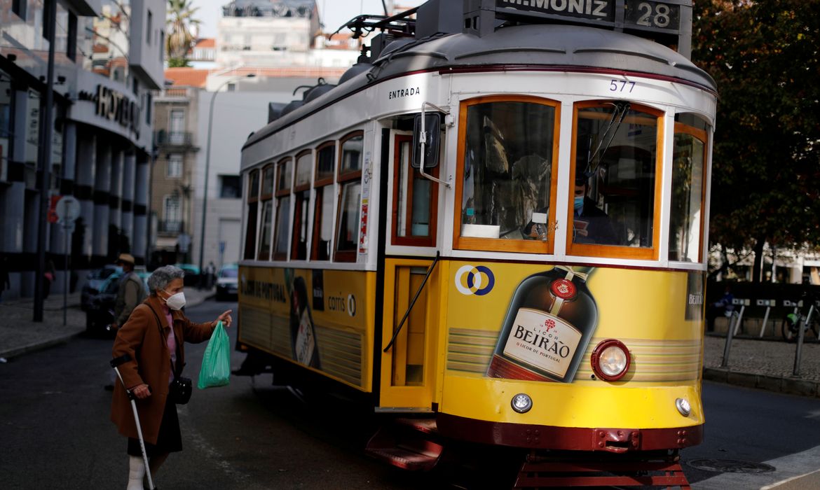 Mulher usando máscara de proteção conversa com motorista de bonde em Lisboa