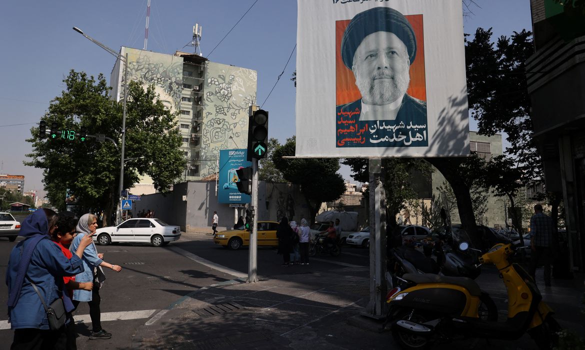 People stand near a banner with a picture of the late Iran's President Ebrahim Raisi on a street in Tehran, Iran May 20, 2024. Majid Asgaripour/WANA (West Asia News Agency) via REUTERS ATTENTION EDITORS - THIS PICTURE WAS PROVIDED BY A THIRD PARTY