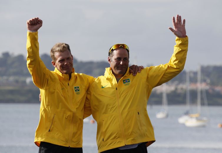 Bronze medallists Brazil's skipper Robert Scheidt and crew Bruno Prada wave during their men's star class keelboat sailing medal race victory ceremony at the London 2012 Olympic Games in Weymouth and Portland