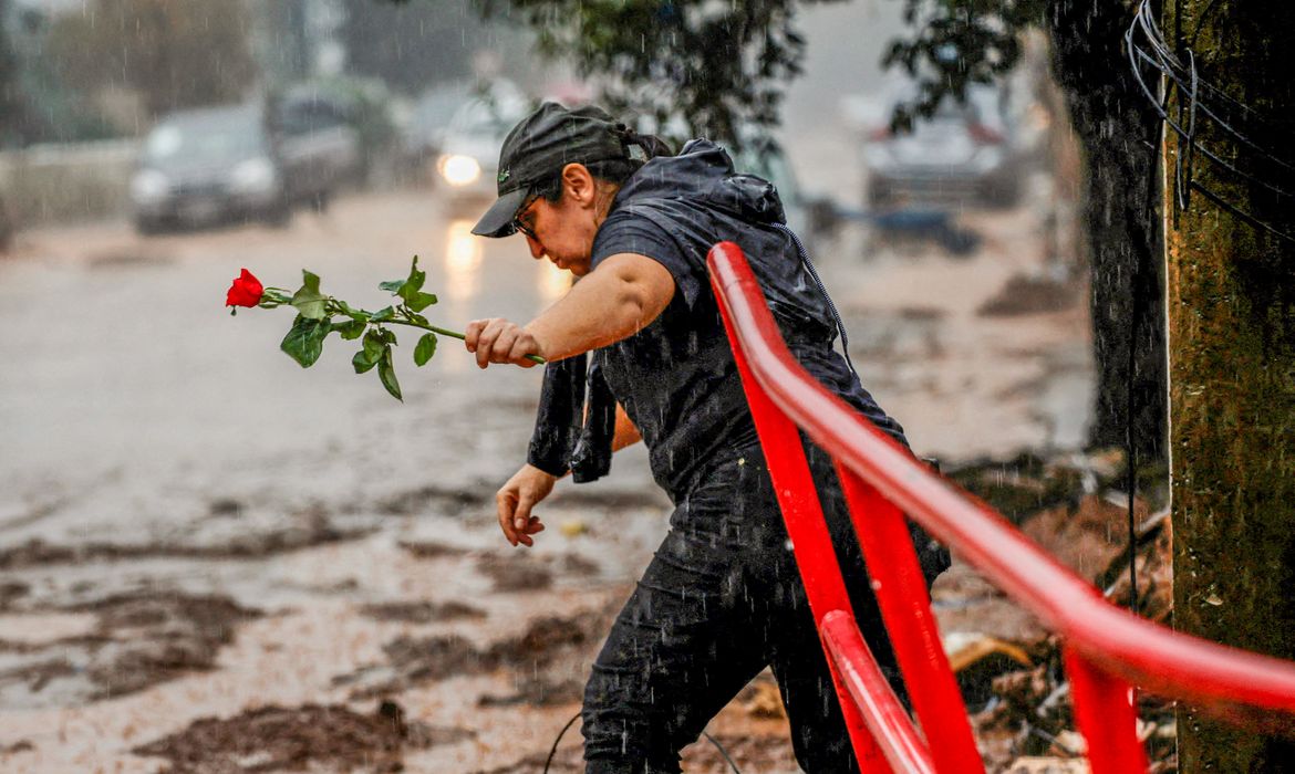 A woman holds a rose as she walks next to a houses partially destroyed after floods in Roca Sales, Rio Grande do Sul state, Brazil May 11, 2024. REUTERS/Adriano Machado