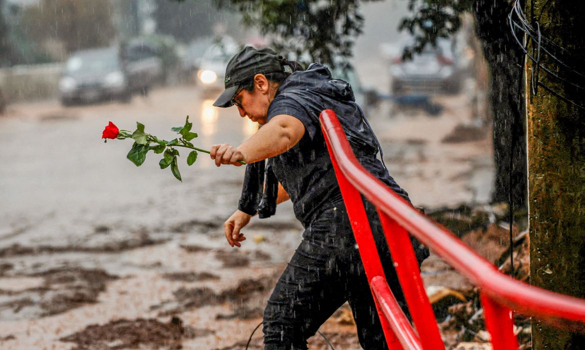 A woman holds a rose as she walks next to a houses partially destroyed after floods in Roca Sales, Rio Grande do Sul state, Brazil May 11, 2024. Reuters/Adriano Machado/Proibida reprodução