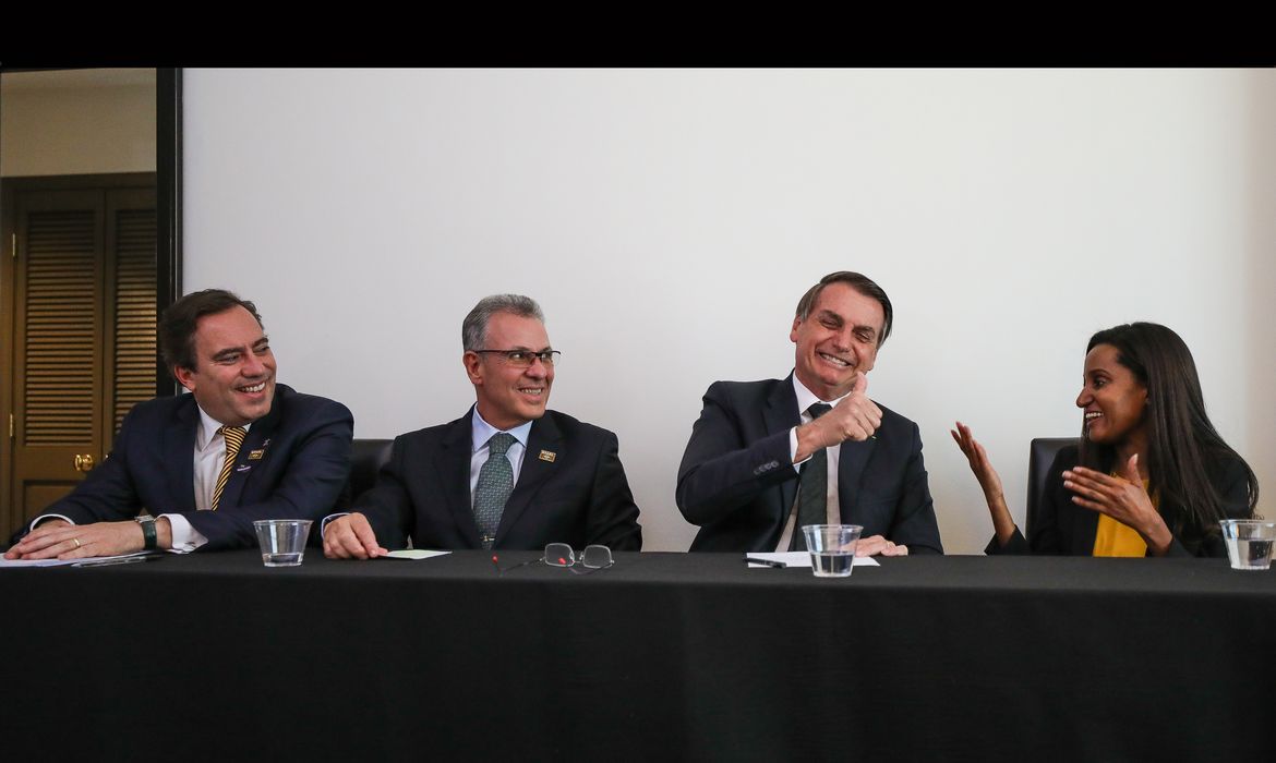 O presidente Jair Bolsonaro, em Dallas (EUA), faz transmissão ao vivo para as redes sociais. ao lado do presidente da Caixa, Pedro Guimarães, do ministro de Minas e Energia, Bento Albuquerque, e da intérprete de libras, Joyce Porto.