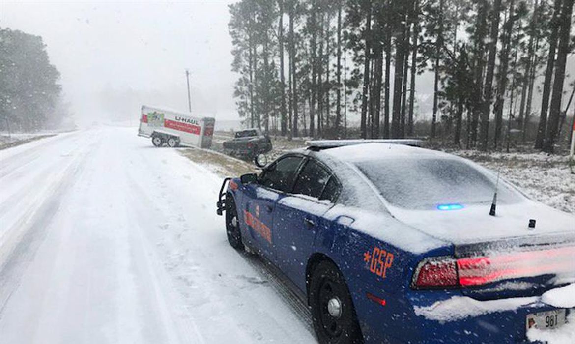 Carro da polícia do condado de Montgomery, no estado da Geórgia, atravessa estrada com neve para prestar socorro a um veículo acidentado durante a onda de frio que atinge os Estados Unidos
