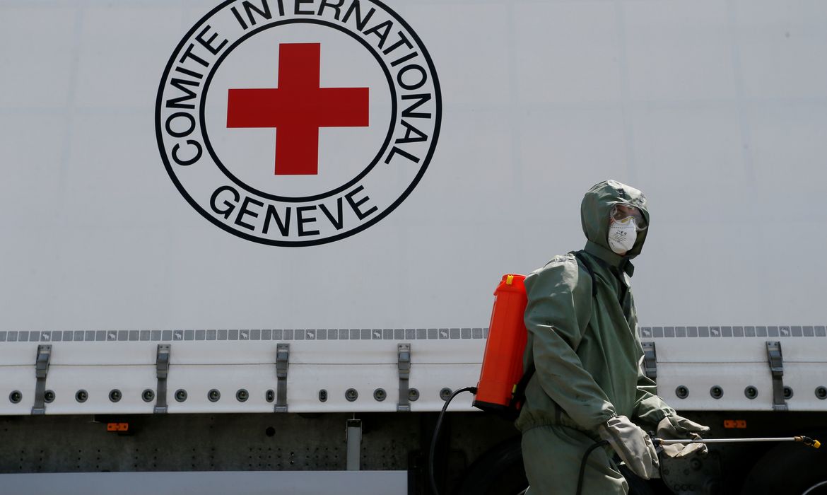 Agente com roupa de proteção desinfecta caminhão em ponto de checagem do Comitê Internacional da Cruz Vermelha em Donetsk
