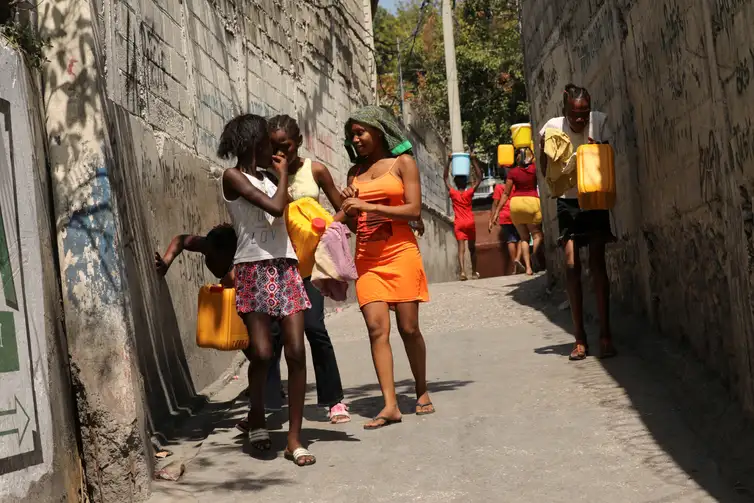 Residents carry water jugs to avoid scarcity at home as the government declared a state of emergency amid violence, in Port-au-Prince, Haiti, March 4, 2024. REUTERS/Ralph Tedy Erol  REFILE - CORRECTING ACTION FROM 