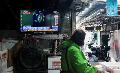 Uma mulher trabalha em uma loja de macarrão perto de uma tela de televisão que exibe uma reportagem sobre os exercícios militares da “Missão de Justiça 2025” da China em torno de Taiwan, em Taipé, Taiwan, em 29 de dezembro de 2025. REUTERS/Tsai Hsin-Han