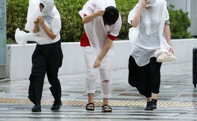Osaka – Transeuntes caminham com dificuldade em meio a fortes rajadas de vento e chuvas provocadas pelo tufão Jebi