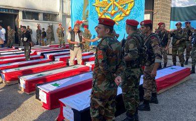 Military police stand near coffins with the bodies of some of the people who were killed in a drone attack on a military academy, outside a military hospital in Homs. REUTERS/Firas Makdesi