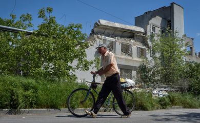 Homem passa em frente a prédio de escola danificado por um ataque de um drone russo em Kherson, na Ucrânia