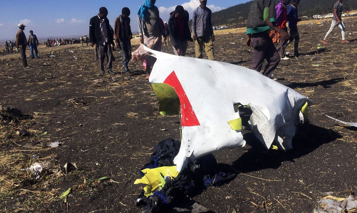 People walk past a part of the wreckage at the scene of the Ethiopian Airlines Flight ET 302 plane crash, near the town of Bishoftu, southeast of Addis Ababa, Ethiopia March 10, 2019. REUTERS/Tiksa Negeri