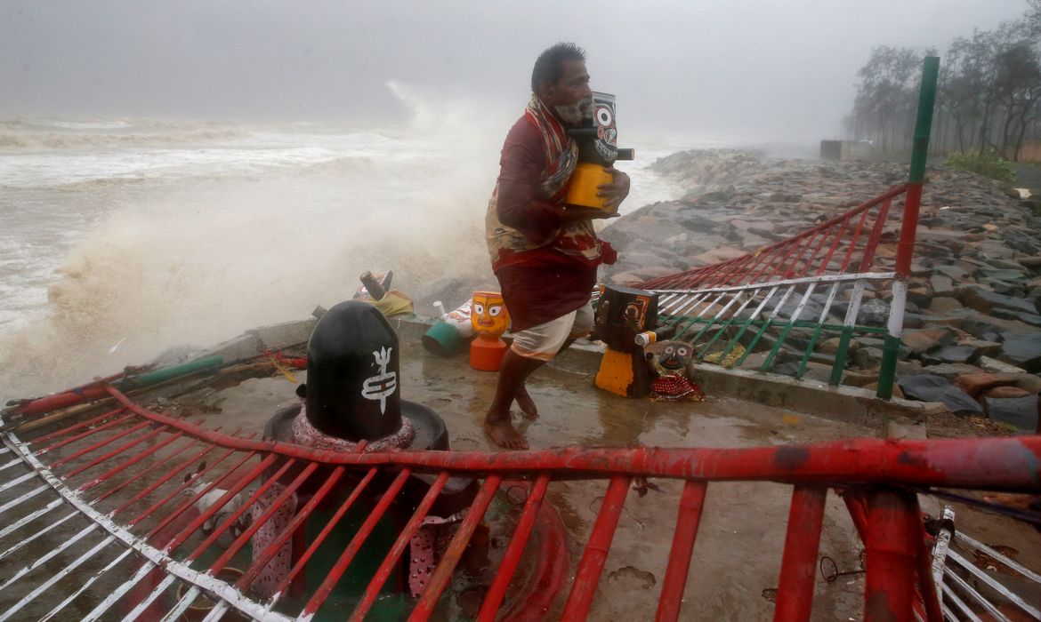 A Hindu priest carries an idol of Lord Jagannath from a seafront temple to a safer place ahead of Cyclone Yaas in Balasore district