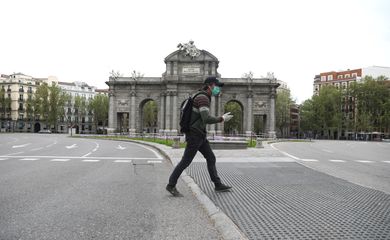 Um homem vestindo uma máscara protetora e luvas passa pelo marco vazio de Alcala Gate, em meio ao surto de doença por coronavírus (COVID-19) em Madri, Espanha, 9 de abril de 2020. REUTERS / Sergio Perez