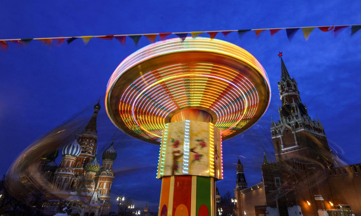 Carrossel em frente a torre do Kremlin e à catedral de São Basílio em Moscou