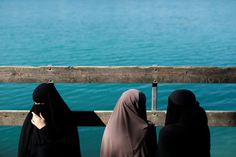 Alaa (L), 21, Amina (C), 24, and Nayab, 18, sit on a dock during a visit to Karlstrup Kalkgrav, a lake near Karlstrup located outside Copenhagen, Denmark, July 19, 2018.  REUTERS/Andrew Kelly    SEARCH 