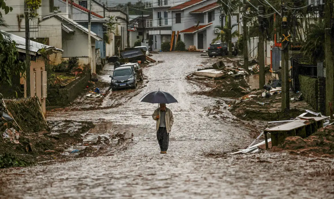 A man with an umbrella walks along a partially destroyed street after floods in Mucum, Rio Grande do Sul state, Brazil May 11, 2024. REUTERS/Adriano Machado
