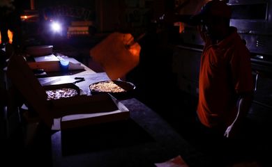 A man cooks with candlelight and lanterns at a pizzeria during a second day of blackout in Caracas, Venezuela March 9, 2019. REUTERS/Marco Bello