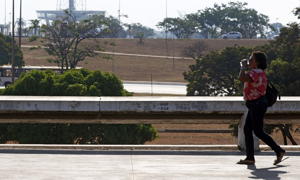 Brasília (DF), 03.09.2024 - Seca e alta temperatura em Brasília. Pessoa com copo de água passa pelo Setor de Diversões Sul.  Foto: Bruno Peres/Agência Brasil