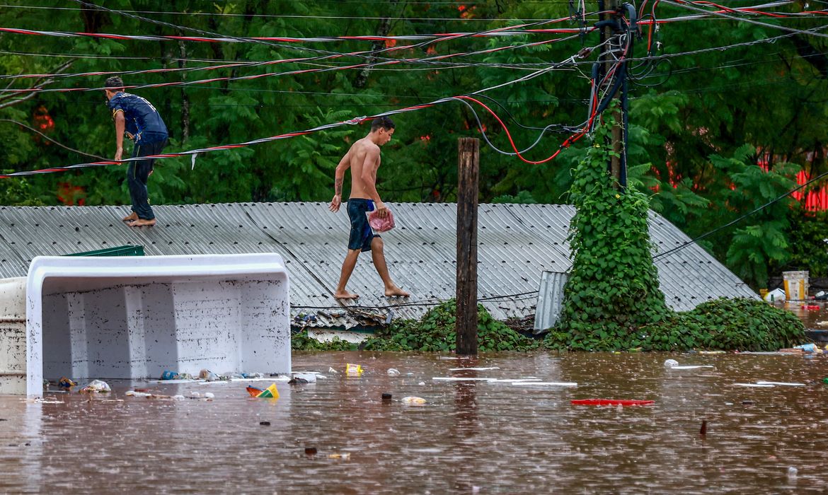 People walk on a roof in a flooded area next to the Taquari River during heavy rains in Encantado, Rio Grande do Sul state, Brazil, May 2, 2024. REUTERS/Diego Vara