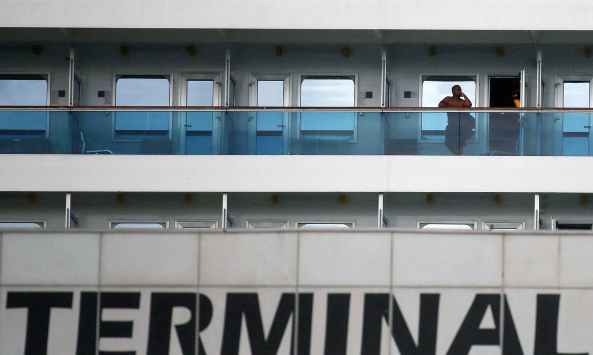 FILE PHOTO: A passenger is seen on the balcony of the Costa Fascinosa cruise ship anchored at the Santos port, amid the coronavirus disease (COVID-19) outbreak, in Santos