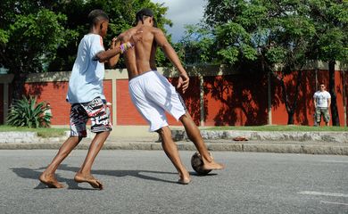 Meninos da comunidade Metrô-Mangueira jogam futebol e interagem com turistas em rua interditada por policiais nos arredores do estádio do Maracanã (Tânia Rêgo/Agência Brasil)