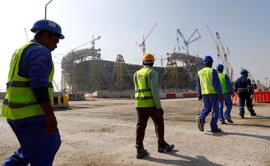Trabalhadores caminham em local de construção de estádio em Doha, Catar