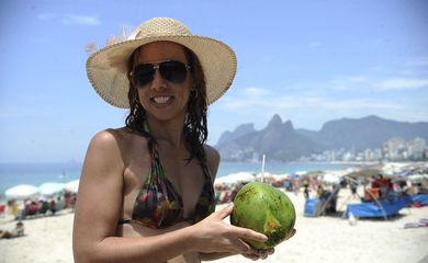 Banhistas combatem calor intenso com banho de mar na praia de Ipanema no último dia de 2014. A enfermeira Jane Leite se protege com chapéu, óculos e água de coco para refrescar (Fernando Frazão/Agência Brasil)
