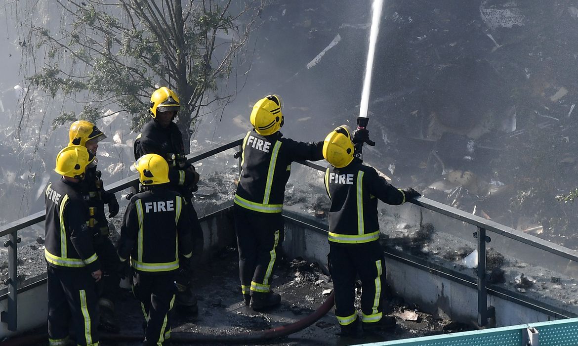 Homens do Corpo de Bombeiros combatem o incêndio de grandes proporções em um edifício de 24 andares em Londres
