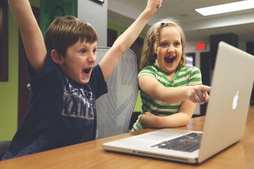 Crianças comemorando ao computador