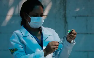 A técnica de enfermagem, Paula Roberta Moreira mostra a ampola da vacina contra a covid-19 antes de aplicar a injeção.