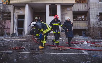 Equipes de resgate ajudam mulher a sair de prédio residencial atingido por ataque aéreo em Kiev