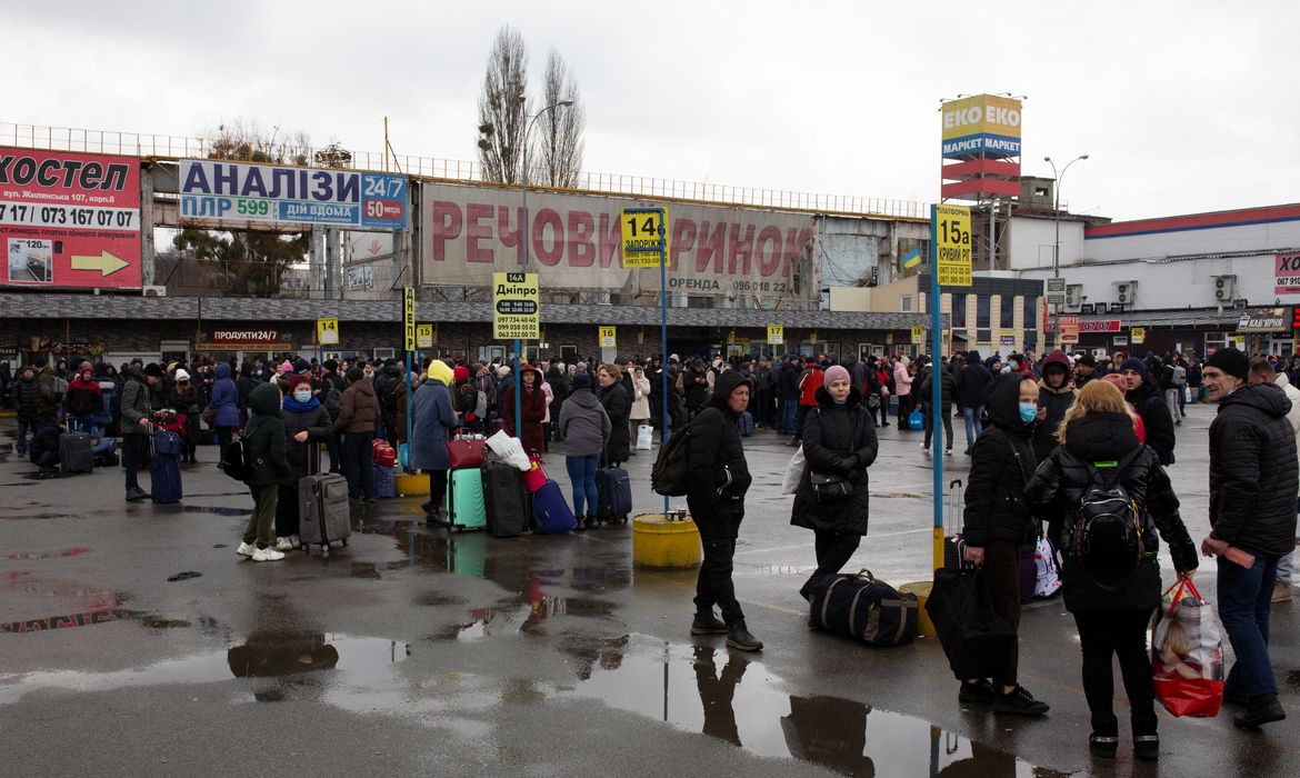 Pessoas se reúnem em uma estação de ônibus enquanto tentam sair de Kiev