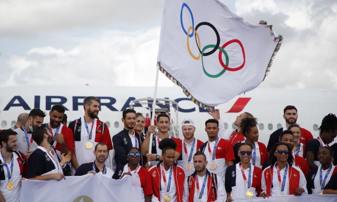 Medalhistas olímpicos franceses desembarcam com bandeira olímpica em aeroporto de Paris