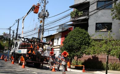 Funcionários da Enel fazem manutenção em poste de energia elétrica no bairro de Pinheiros.