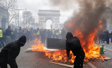 Os manifestantes reagem ao lado de uma barricada em chamas, durante uma demonstração do movimento 