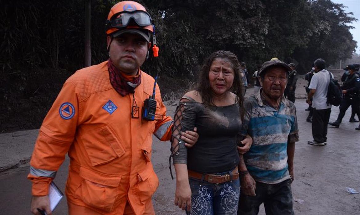 Trabalhador ajuda no resgate de moradores atingidos pela erupção do Vulcão Fogo