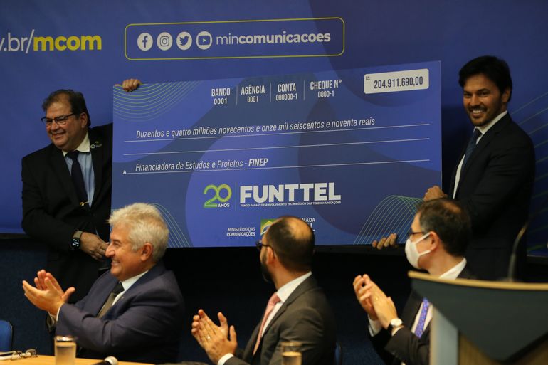O presidente da FINEP, general Waldemar Barroso, recebe do  ministro das Comunicações, Fábio Faria, um cheque, durante a cerimônia em comemoração aos 20 Anos do Fundo para o Desenvolvimento Tecnológico das Telecomunicações (Funttel)